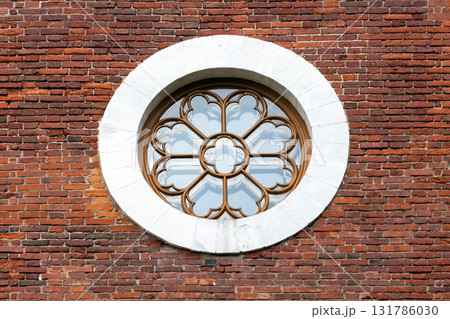 A decorative circular window with intricate frame sits in a white stone circle A decorative circular window with intricate frame sits in a white stone circle 131786030