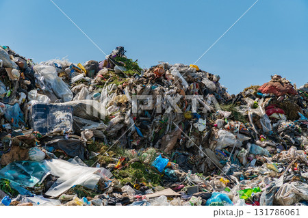 A large mound of garbage sits under a clear blue sky, showcasing the significant waste problem affecting our ecology 131786061