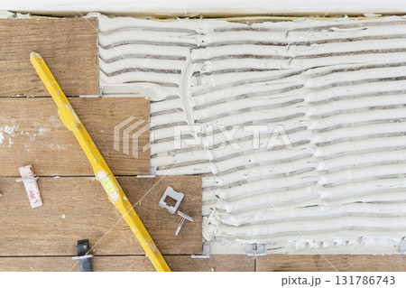 Process of tiling a room, tiles and floor prepared with adhesive, top view. Construction of a house Process of tiling a room, tiles and floor prepared with adhesive, top view. Construction of a house 131786743