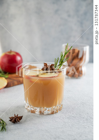 Hot apple cider with cinnamon, anise, and rosemary in glass on a light background Hot apple cider with cinnamon, anise, and rosemary in glass on a light background 131787344