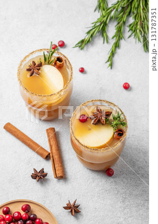 Two glasses of hot apple cider with cinnamon, anise, brown sugar and rosemary on a light background 131787351