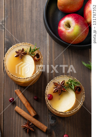 Two glasses of hot apple cider with cinnamon, anise, brown sugar and rosemary on a wooden background Two glasses of hot apple cider with cinnamon, anise, brown sugar and rosemary on a wooden background 131787352