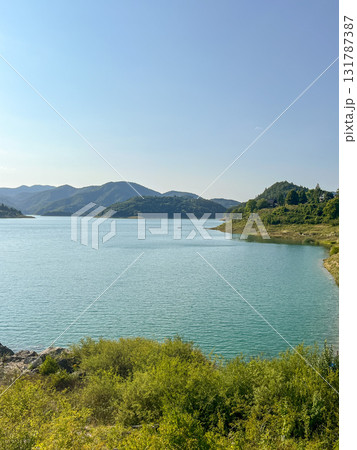 Panoramic and picturesque view of a lake with calm water against the backdrop of forested hills. Panoramic and picturesque view of a lake with calm water against the backdrop of forested hills. 131787387