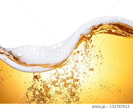 A splash of yellow beer is poured into a clear glass, creating white foam on a white background. 131787615