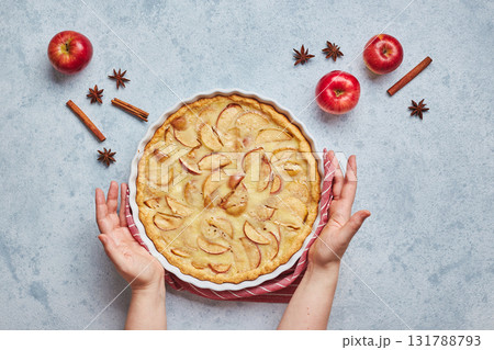 Female hands and homemade apple pie with sour cream filling on light background, top view. 131788793