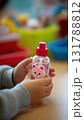 Child's Hands Using Character-Shaped Sanitizer Bottle for Hygiene at School 131788812