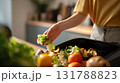 Close-up of Woman Disposing Salad Scraps in Modern Kitchen Setting 131788823