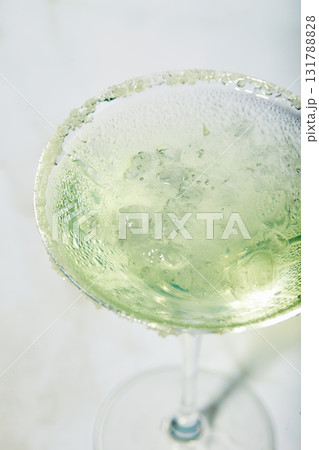Martini cocktail with ice and slice of lime on marble table background. Alcoholic cocktail or non-alcoholic mocktail. Martini cocktail with ice and slice of lime on marble table background. Alcoholic cocktail or non-alcoholic mocktail. 131788828