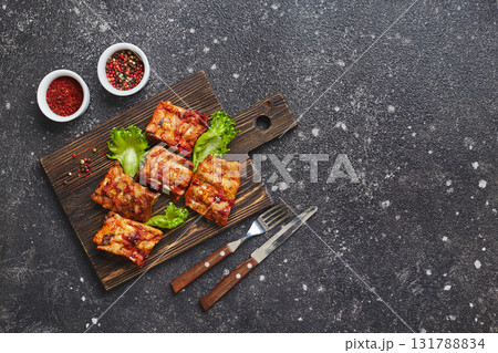 Grilled baked pork ribs with spices and vegetables on wooden cutting board on dark background. American food concept. Top view, copy space. Grilled baked pork ribs with spices and vegetables on wooden cutting board on dark background. American food concept. Top view, copy space. 131788834