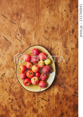 Plate with small red apples - Crabapples, on warm wooden background Plate with small red apples - Crabapples, on warm wooden background 131788841