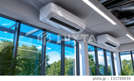Modern office interior with sleek air conditioner system on ceiling for cooling and climate control, offering peaceful view of nature through large glass window Modern office interior with sleek air conditioner system on ceiling for cooling and climate control, offering peaceful view of nature through large glass window 131789030