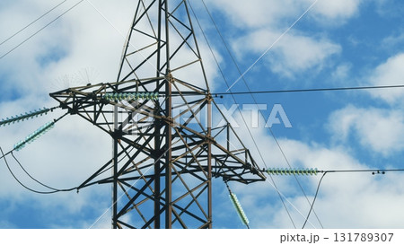 High Voltage Power Lines Stretching Against a Beautiful Blue Sky with Fluffy Clouds 131789307