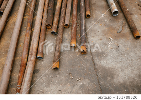 Rusty Metal Pipes Arranged on Concrete Surface 131789320