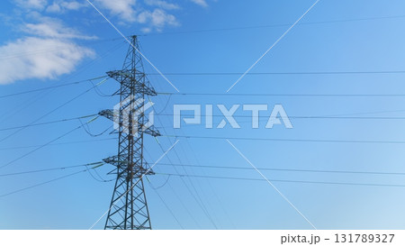 High Voltage Power Lines Stretching Against a Clear Blue Sky, Towering Above the Landscape 131789327
