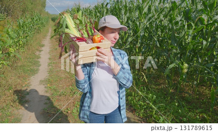 A woman is harvesting fresh vegetables in a green field, showing her dedication to agriculture 131789615