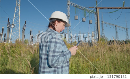 A Professional Worker is seen collaborating and communicating using a Smartphone at a Power Station 131790181