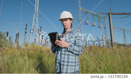 A skilled engineer is actively assessing and analyzing equipment within a wind farm setting A skilled engineer is actively assessing and analyzing equipment within a wind farm setting 131790189