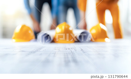 Construction team reviewing blueprints with safety helmets on site 131790644