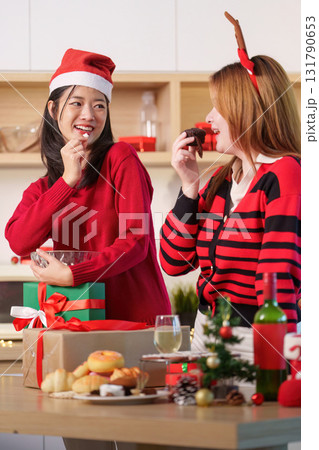 Holiday Fun. Friends enjoying Christmas treats and exchanging gifts in a cozy kitchen. 131790653