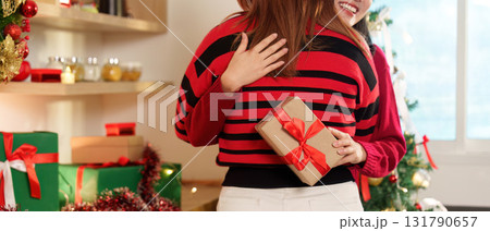 Christmas Celebration. Two friends sharing a warm hug with a gift in a festive setting. Christmas Celebration. Two friends sharing a warm hug with a gift in a festive setting. 131790657