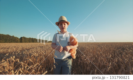 A joyful child plays in a wheat field, holding a teddy bear, embodying innocence and freedom 131790821