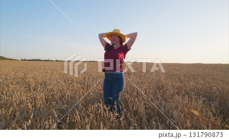 A joyful woman is dancing freely and playfully in a beautiful wheat field under the sun A joyful woman is dancing freely and playfully in a beautiful wheat field under the sun 131790873