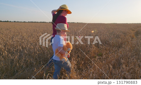 A Mother and Her Child are Enjoying a Relaxed Walk Together in a Beautiful Wheat Field at Sunset A Mother and Her Child are Enjoying a Relaxed Walk Together in a Beautiful Wheat Field at Sunset 131790883