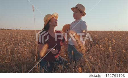 A mother lovingly interacts with her child in a golden wheat field during a beautiful sunset 131791108