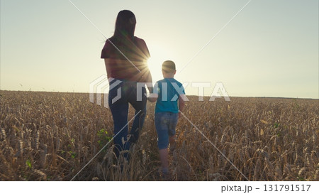 A Mother and Her Child Happily Walking Together Through a Bright and Sunlit Field A Mother and Her Child Happily Walking Together Through a Bright and Sunlit Field 131791517