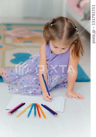A Creative Young Girl Enthusiastically Drawing with Colorful Pens and Markers on the Floor A Creative Young Girl Enthusiastically Drawing with Colorful Pens and Markers on the Floor 131791551