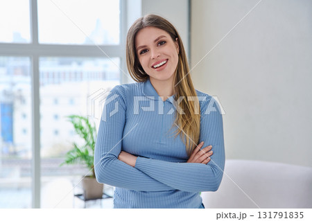 Portrait of confident young woman posing with crossed arms in home interior 131791835