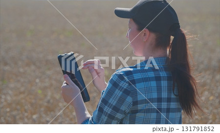 A young woman is using her smartphone while standing in a vast open field, embracing technology 131791852