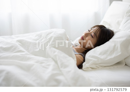 朝の光に包まれて白いベッドで眠る女性 131792579