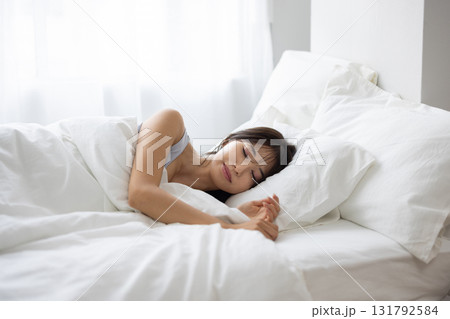朝の光に包まれて白いベッドで眠る女性 131792584