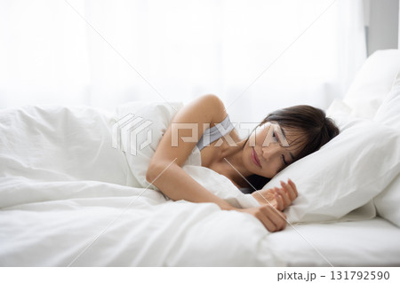 朝の光に包まれて白いベッドで眠る女性 朝の光に包まれて白いベッドで眠る女性 131792590
