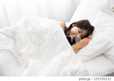 朝の光に包まれて白いベッドで眠る女性 131793212