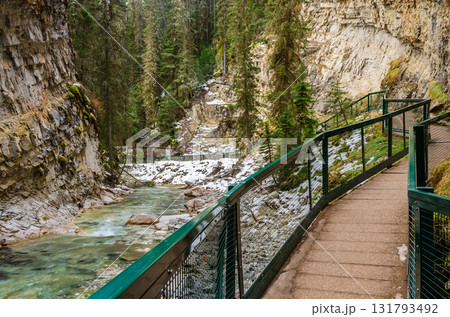 Green boardwalk guides viewer through snowy Johnston canyon with clear turquoise stream in winter season in Banff National Park, Alberta, Canada Green boardwalk guides viewer through snowy Johnston canyon with clear turquoise stream in winter season in Banff National Park, Alberta, Canada 131793492