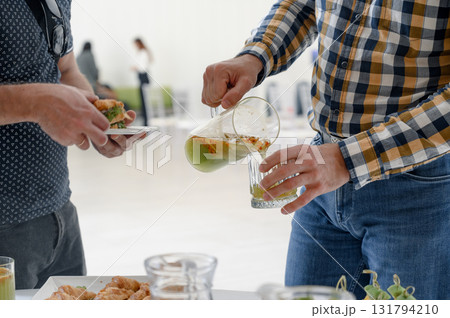 A man in a plaid shirt pours lemonade for a guest at a business reception. A man in a plaid shirt pours lemonade for a guest at a business reception. 131794210
