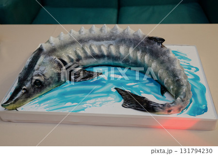 A close-up of a sturgeon-shaped birthday cake on a rectangular stand 131794230