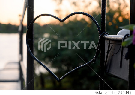 A forged metal heart on a pier railing with a blurred river background A forged metal heart on a pier railing with a blurred river background 131794343