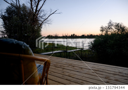 Wooden deck and viewing platform by a river against the backdrop of sunset 131794344