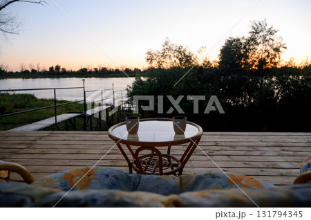 Wooden deck and viewing platform by a river against the backdrop of sunset 131794345