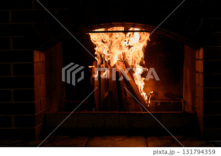 A bright fire in the firebox of a large brick outdoor or garden fireplace. A bright fire in the firebox of a large brick outdoor or garden fireplace. 131794359