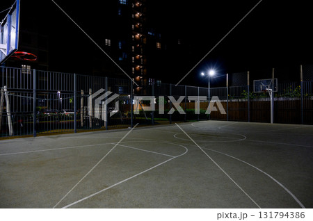 A basketball court in the courtyard of a residential complex at night A basketball court in the courtyard of a residential complex at night 131794386