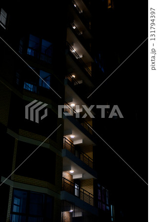 Night illumination of balconies of a tall building against the black sky. 131794397
