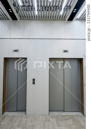 Modern elevator lobby with two metal doors and designer ceiling. 131794400
