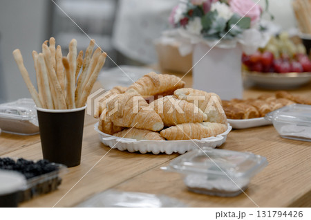 Croissants and breadsticks on a wooden table during a coffee break. Croissants and breadsticks on a wooden table during a coffee break. 131794426