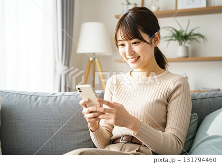 ソファに座ってスマホを見る女性 131794460