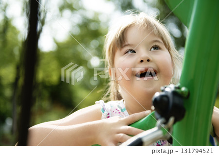 A portrait of trisomie 21 child girl outside having fun on a park A portrait of trisomie 21 child girl outside having fun on a park 131794521