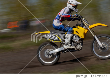 Blurred motion motocross rider riding uphill on track 131794647